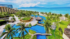 A resort with a large pool, palm trees, and a view of the ocean. - Crowne Plaza Danang by IHG (Da Nang)