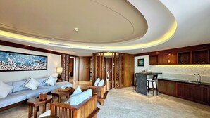 A modern living room with a sofa, coffee table, and a kitchen area with a bar. - Crowne Plaza Danang by IHG (Da Nang)