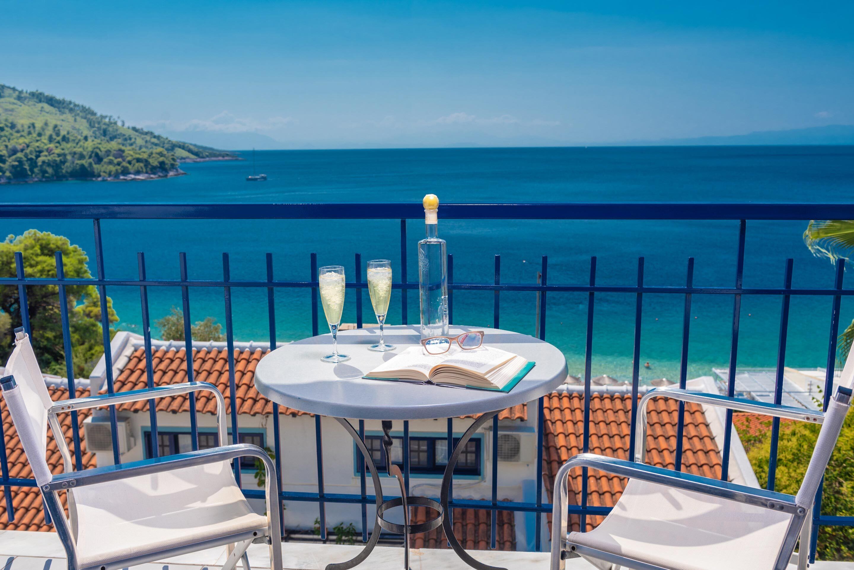 Un balcon avec une table dressée pour deux personnes, offrant une vue sur la côte.