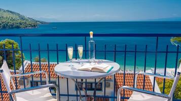 Un balcón con una mesa lista para dos personas, con vista al mar.
