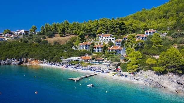 Un hôtel situé sur la côte, composé de plusieurs bâtiments, avec une plage et une jetée.