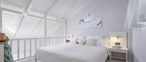 Un dormitorio con una cama grande, una mesita de noche, un ventilador de techo y un cuadro en la pared.