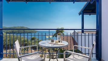 Un balcón con una mesa dispuesta para dos, con vistas panorámicas al mar y las colinas.