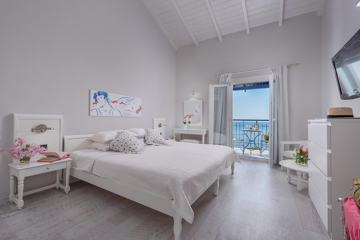 Une chambre à coucher avec un lit, des tables de chevet, une commode et une vue sur la mer.