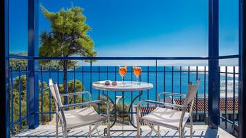 Un balcon avec une table, deux chaises et deux verres de boisson à l’orange.