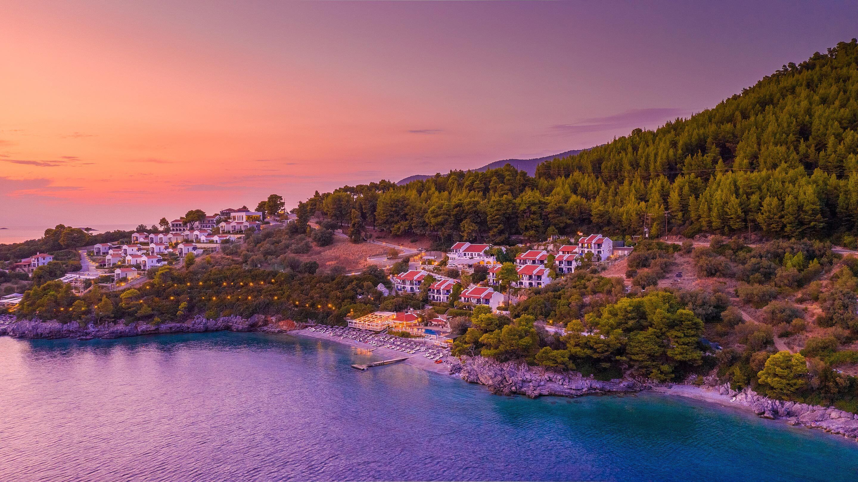 A coastal village with houses on a hillside overlooking a calm sea.