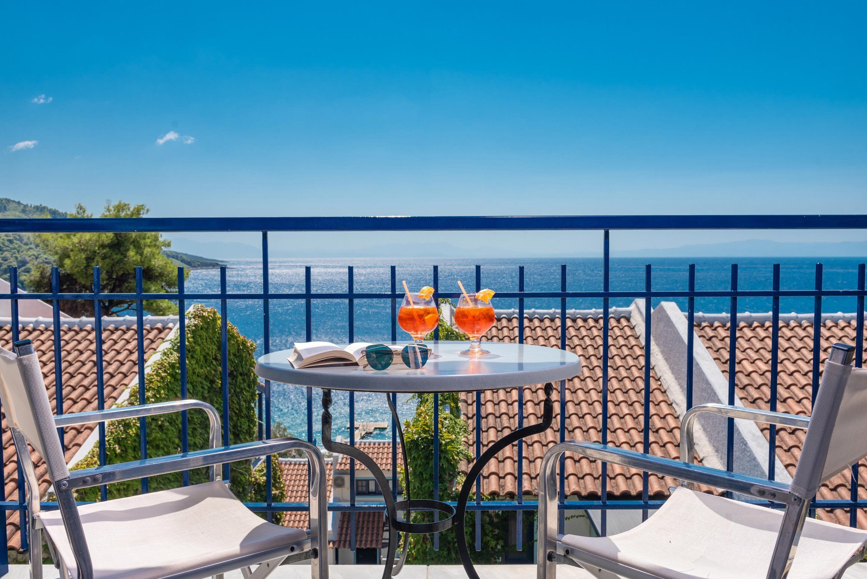 A balcony with a table, two chairs, and two drinks.