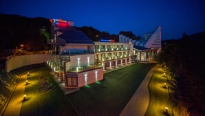 Un hotel de diseño moderno, con una amplia fachada de vidrio, varios balcones y un espacio exterior luminoso con senderos.