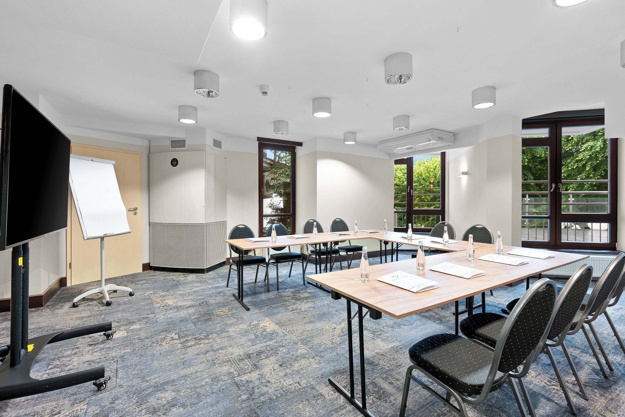 Un salón de conferencias con una larga mesa, sillas, una pizarra y un proyector.