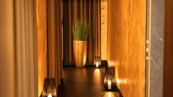 A hallway with wooden walls, a potted plant, and two lit candles.