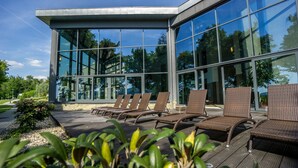 Un edificio moderno con amplios ventanales y una terraza con sillones de descanso.