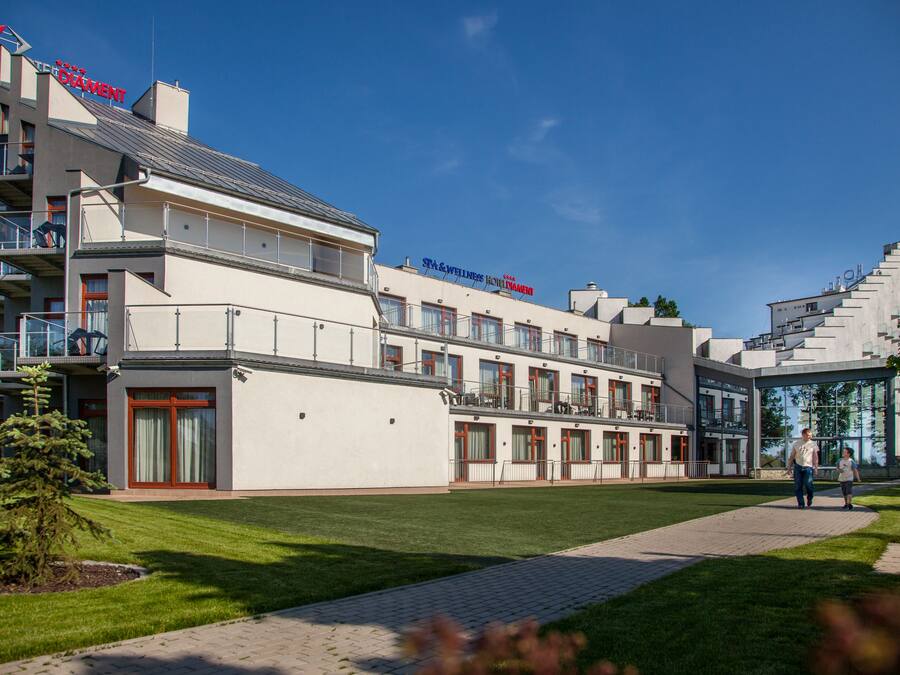 A modern hotel with multiple floors, a well-maintained lawn, and a clear blue sky.