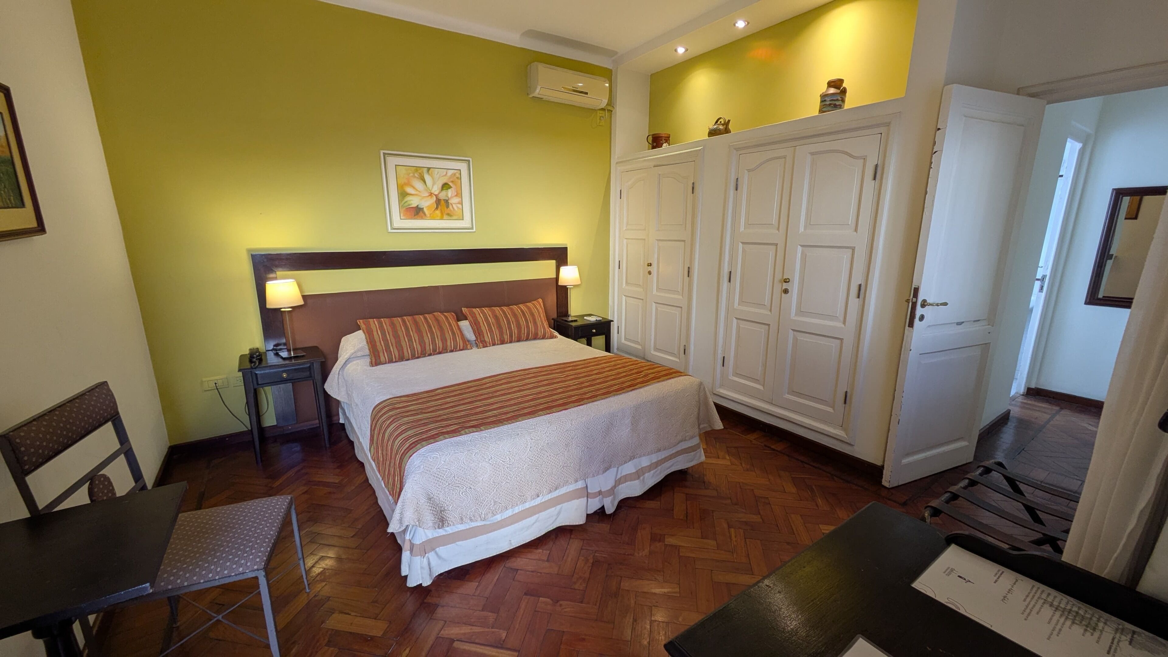 Un dormitorio con cama, mesita de noche, silla, armario y escritorio con silla.