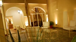 Un espace intérieur bien éclairé, aménagé avec des sièges, une grande fenêtre avec des rideaux et une plante en pot.