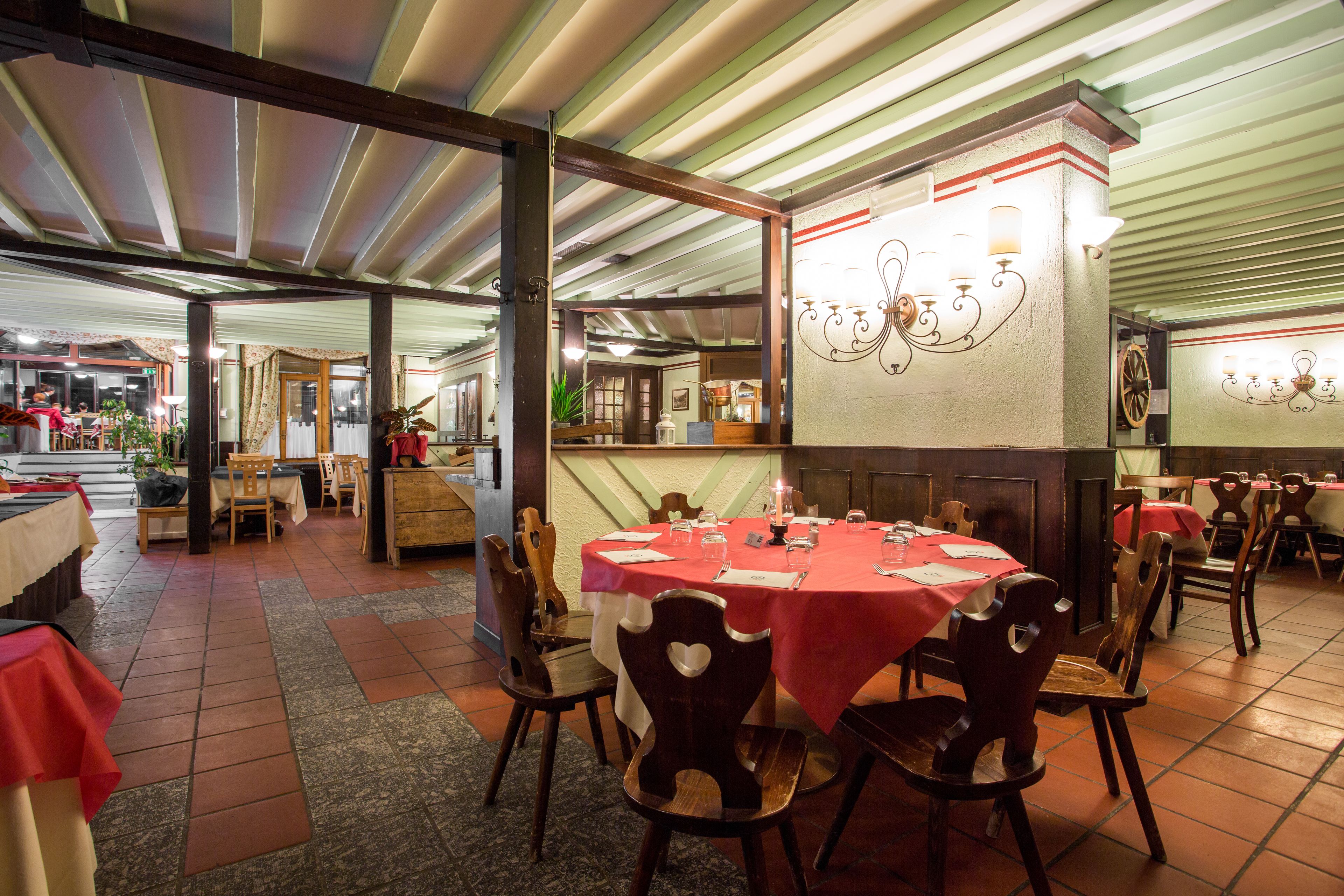 Un ristorante con diversi tavoli e sedie, un pavimento piastrellato e un soffitto a righe verdi.