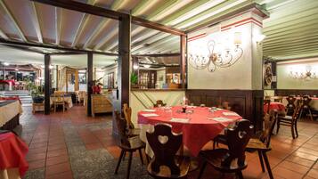 Un ristorante con diversi tavoli e sedie, un pavimento piastrellato e un soffitto a righe verdi.