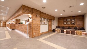 Ein Empfangsbereich mit Holztresen, einer Sitzgelegenheit mit Bänken und gerahmten Bildern an der Wand.