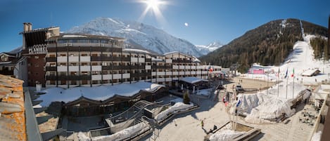 A hotel with multiple floors, a ski slope in the background, and snow-covered surroundings.