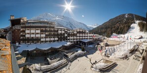 Een hotel met meerdere verdiepingen, een skipiste op de achtergrond en besneeuwde omgeving.