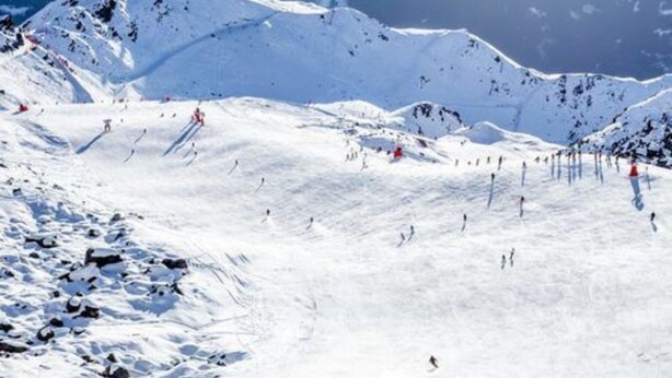 Une piste de ski enneigée, avec des skieurs et des snowboardeurs.
