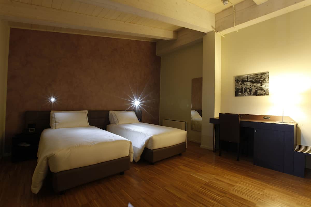 A bedroom with two beds, a desk, and a chair.