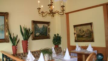 Un comedor con mobiliario de madera, plantas en macetas y cuadros en las paredes.
