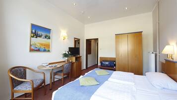 Een hotelkamer met een bed, een bureau met stoel, een televisie en een kledingkast.