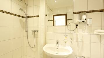 Ein Badezimmer mit Dusche, Waschbecken und Spiegel.
