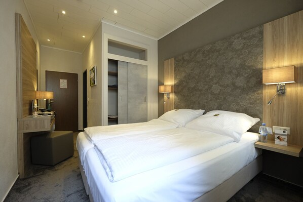 A hotel room with a large bed, bedside tables, a mirror, and a wardrobe. - Hotel Karl Noss (Cochem)