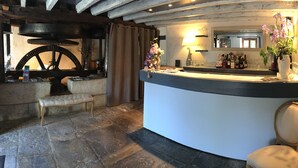 A bar area with a stone floor, a bench, a counter with a mirror, and a vase with flowers.