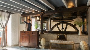 A rustic interior with exposed wooden beams, a stone fireplace, and a wooden bench.