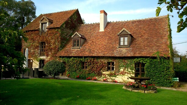 A traditional stone building with ivy-covered walls and a tiled roof.