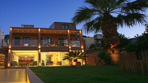 Una casa moderna de dos pisos con balcón, césped cuidado y una palmera.