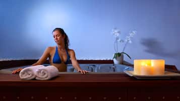 Experience a serene spa setting with a warm and inviting atmosphere, complete with a wooden reception desk, a potted orchid, and a lit candle.