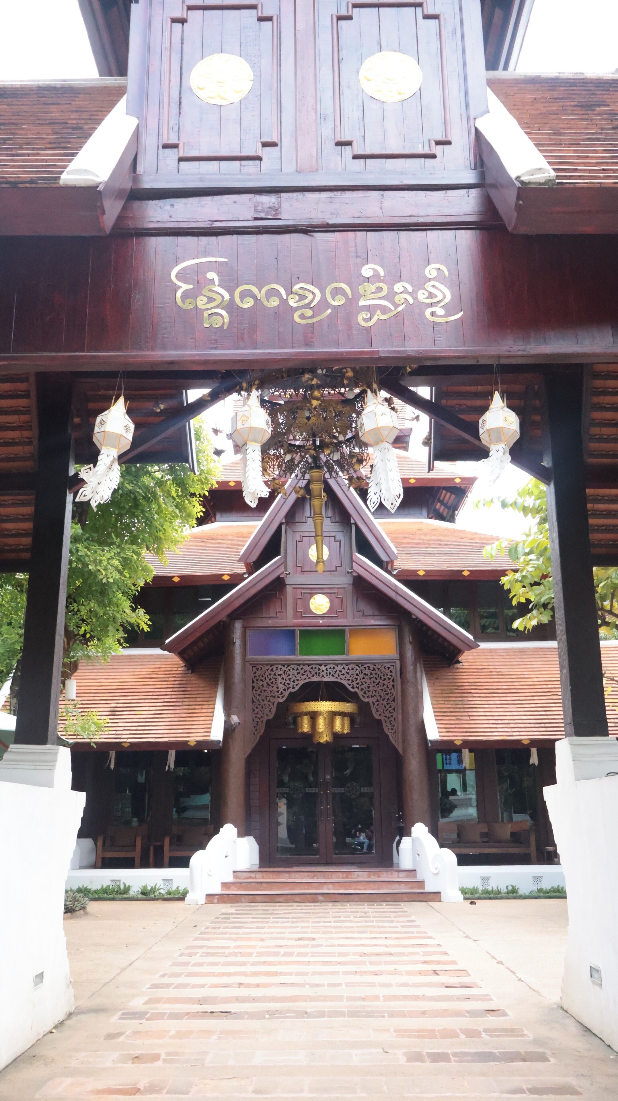 A traditional wooden building with a large entrance, ornate decorations, and a sign with text.