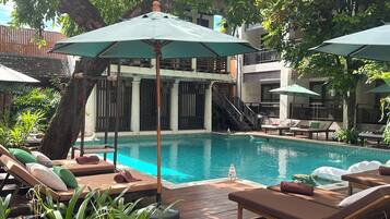 Una piscina al aire libre, sillones reclinables de piscina