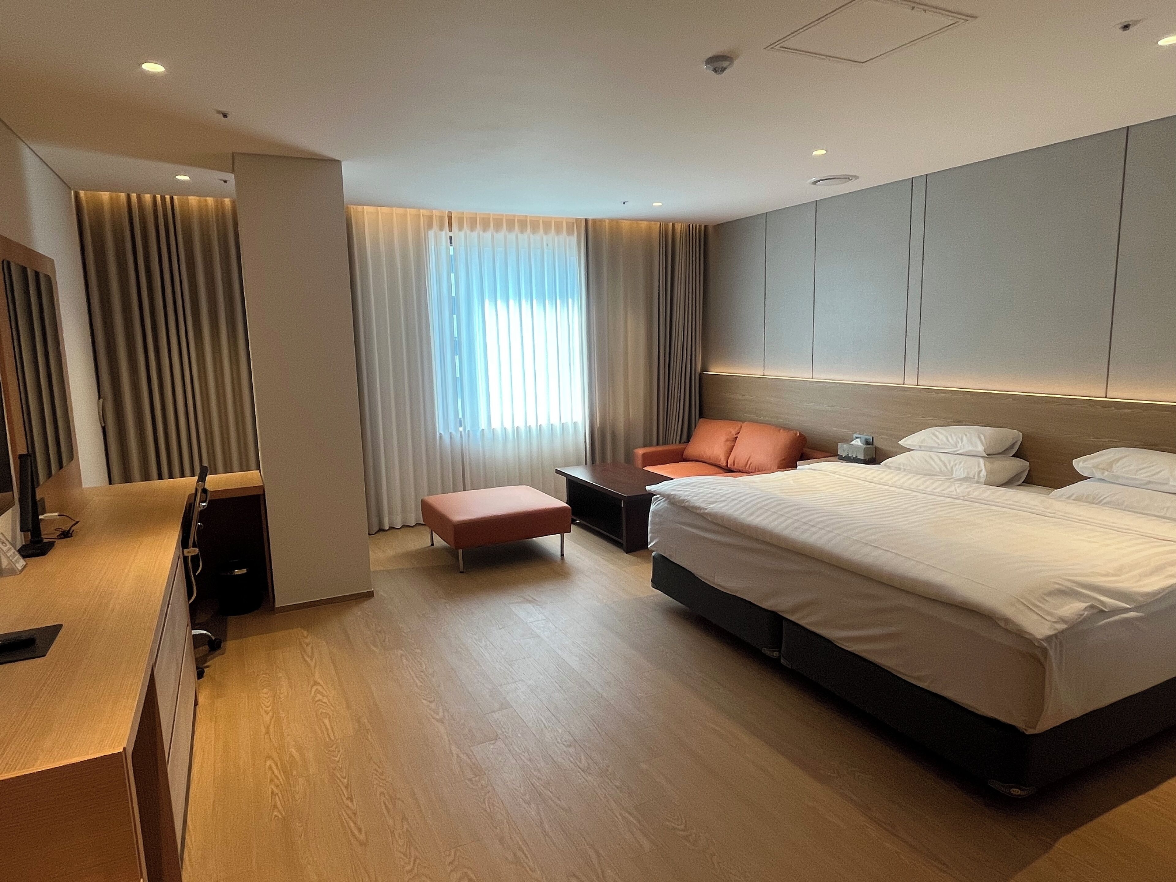 Moderni hotellihuone, jossa on suuri sänky, työpöytä, tuoli ja televisio.