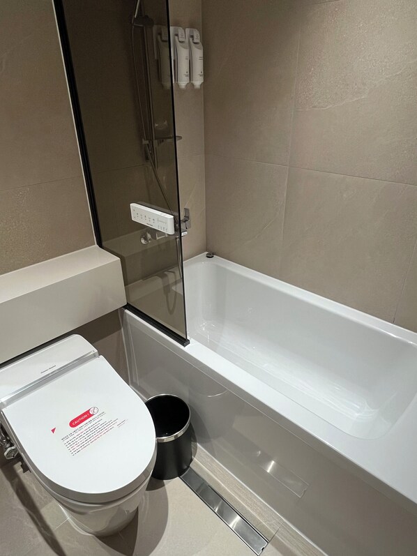 Un baño con inodoro, bañera y zona de ducha.