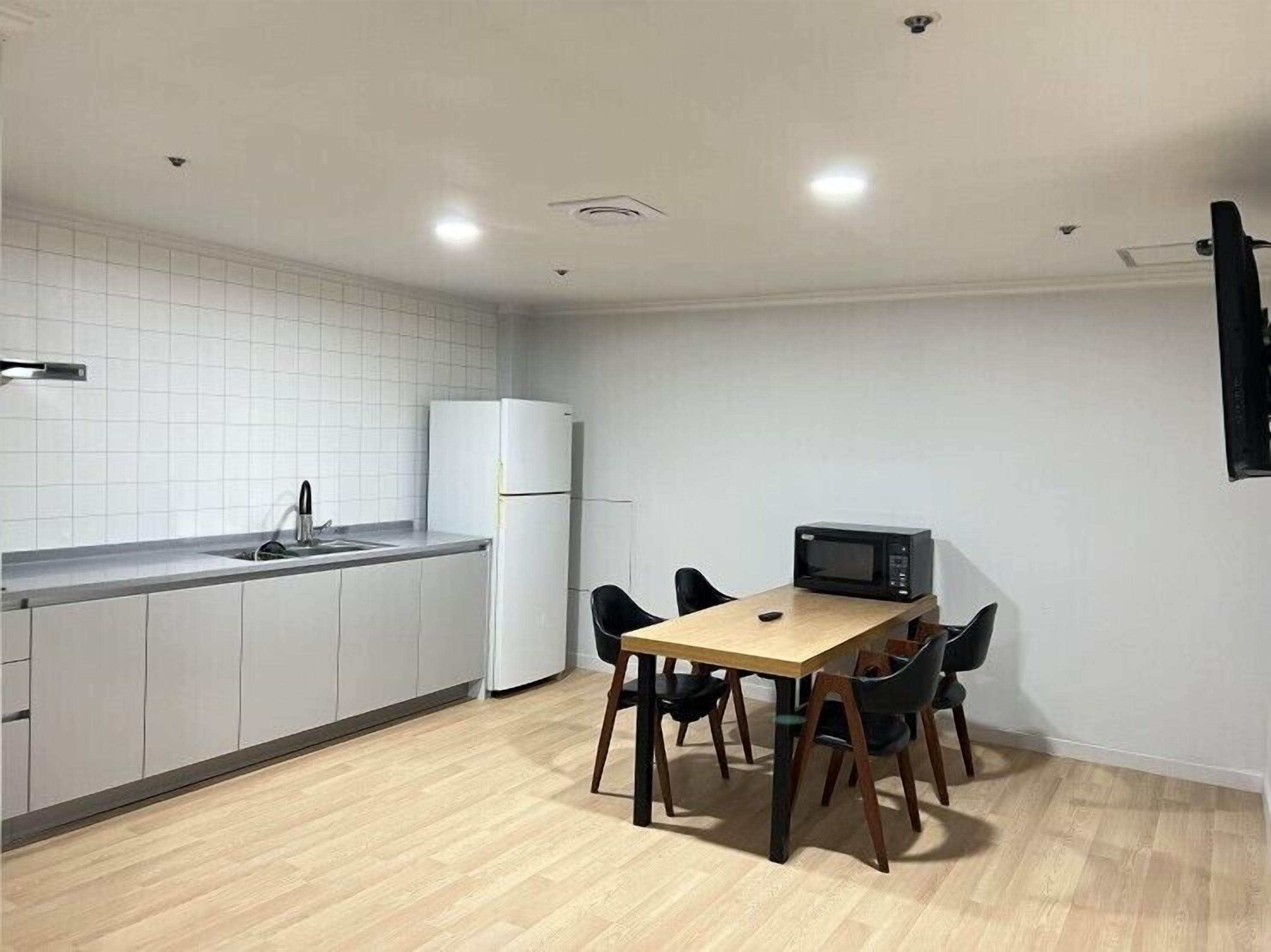 A compact kitchen with a dining table, chairs, a microwave, and a refrigerator.