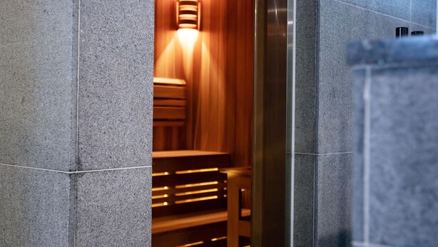 A modern interior with a stone column, a wooden bench, and a glass partition. - Hotel International (Changwon)