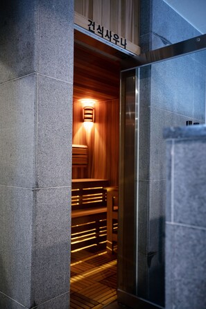 A modern interior with a stone column, a wooden bench, and a glass partition. - Hotel International (Changwon)