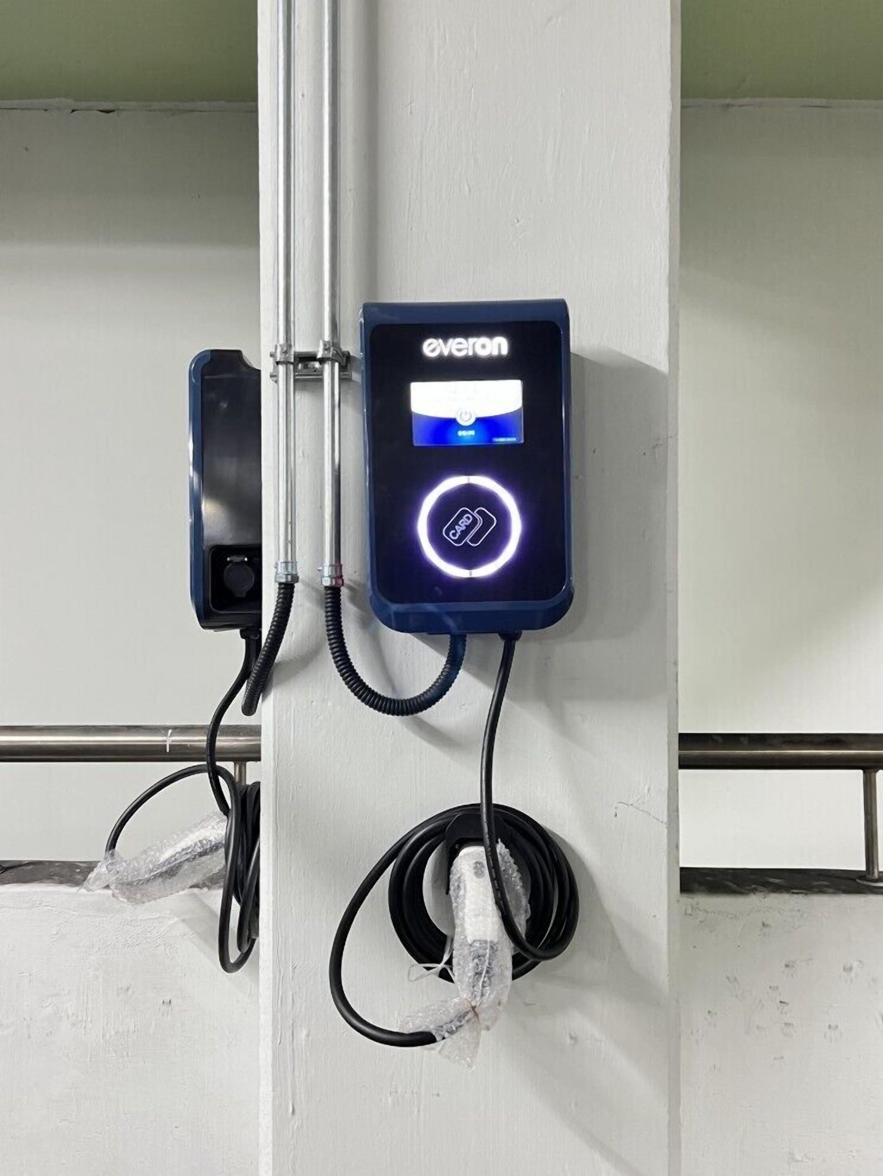 Estación de carga para vehículos eléctricos, fijada a la pared, con la marca 'everon', una ranura para tarjeta y una luz indicadora circular.