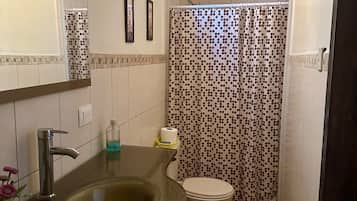 A bathroom with a glass sink, a toilet, and a shower curtain with a polka dot pattern.