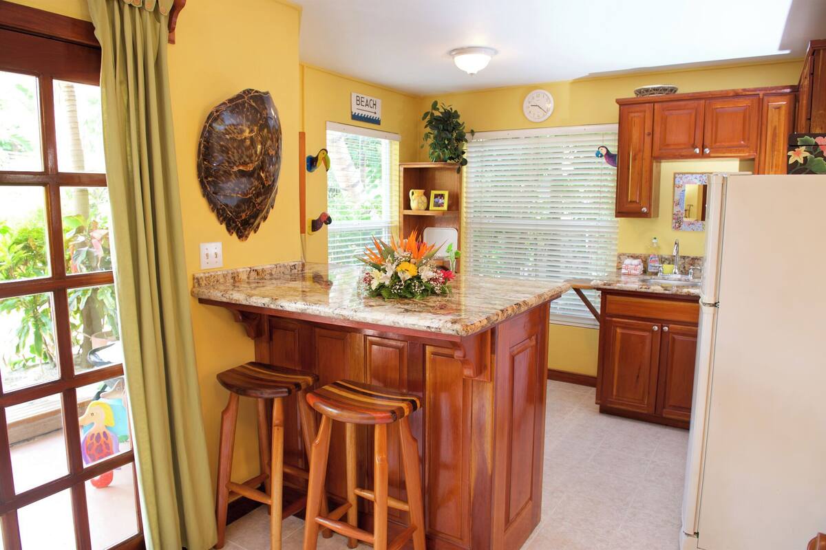 A kitchen with wooden cabinets, a marble countertop, and a central island with stools.