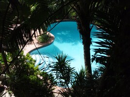 Een buitenzwembad, ligstoelen bij het zwembad