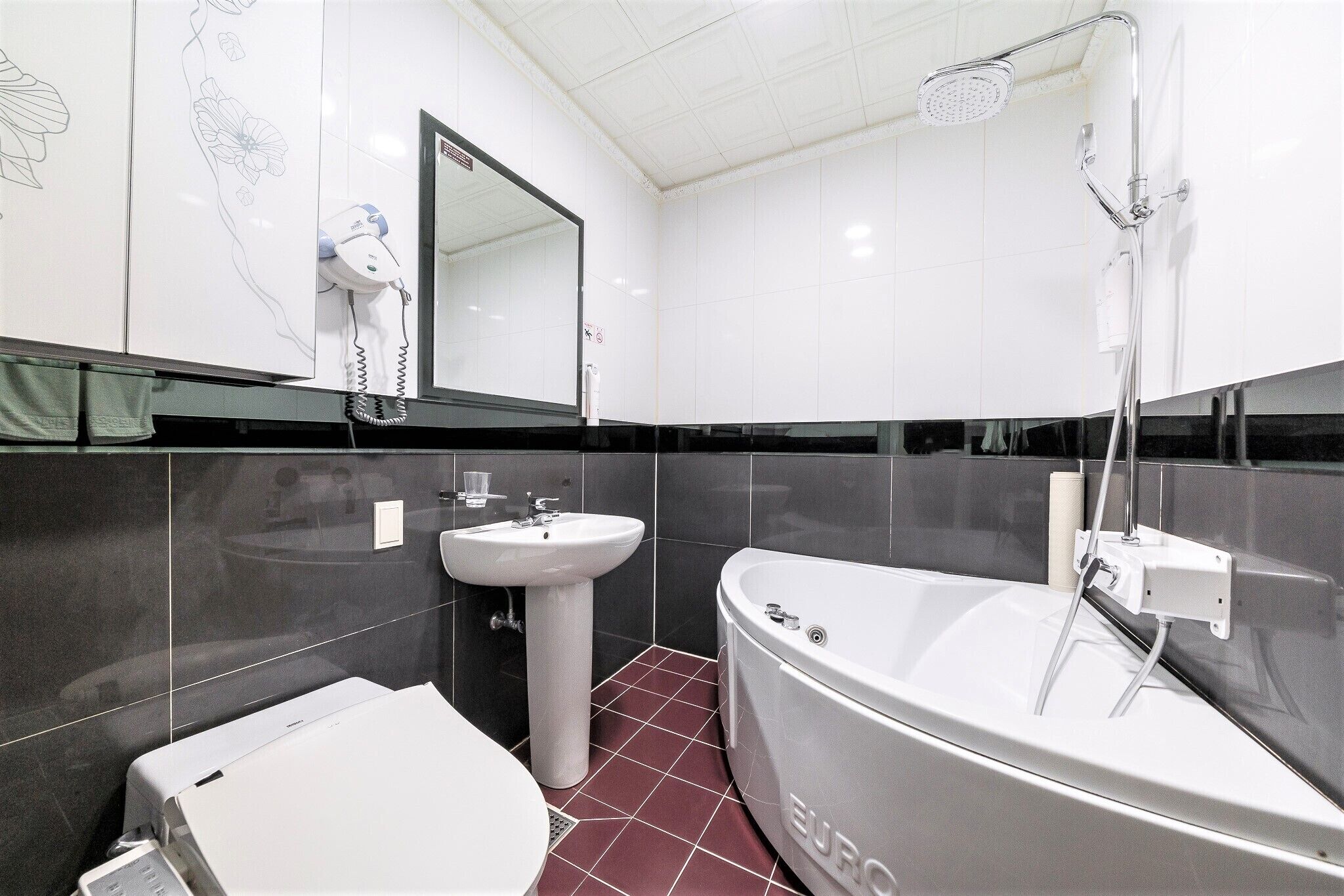 A bathroom with a white bathtub, a pedestal sink, and a toilet.