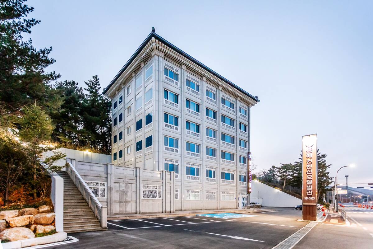Ein mehrgeschossiges Gebäude mit moderner Architektur, das eine markante Eingangspforte mit Treppe und dekorativen Elementen aufweist.