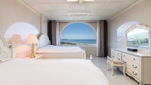 Ein Schlafzimmer mit einem großen Bett, einem Schminktisch und Blick auf das Meer.