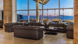 A spacious lobby with large windows, leather sofas, and a modern design.
