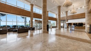 A spacious lobby with large columns, a revolving door, and a reception desk.